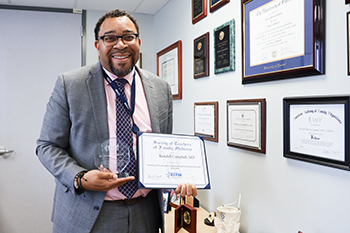 Dr. Kendall M Campbell show his award he received in recognition of his service as co-founder and faculty leader of the Leadership Through Scholarship Fellowship Program from STFM