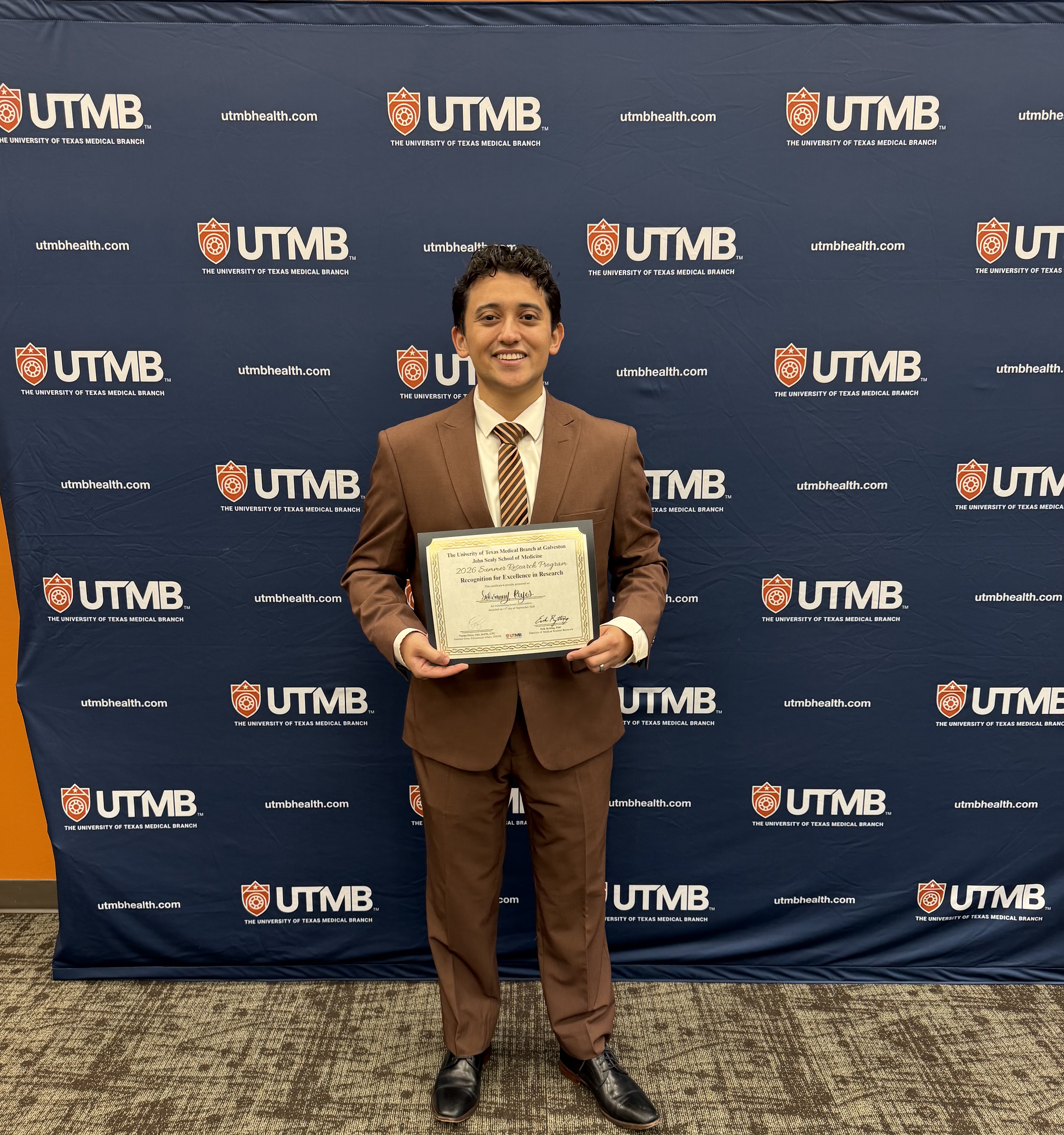 Photo of Giovanny Reyes winning award of excellence in research as part of the summer research program symposium
