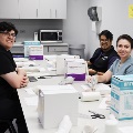 Group of students seated around a table with boxed supplies and lab materials during a hands-on training session in a classroom setting.