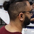 Side profile of a student wearing glasses in a classroom setting with blurred background of clinical equipment and workstations.
