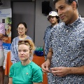 Small group of students and an instructor stand together in a clinical learning space, listening and participating in a discussion during a training session.