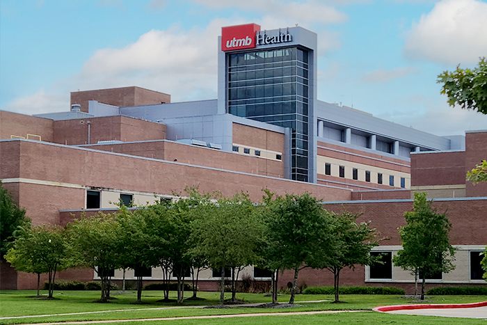 Exterior view of a UTMB Health medical center building with landscaped grounds.