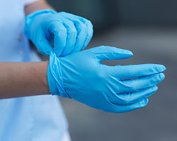 A pair of hands wearing blue latex gloves