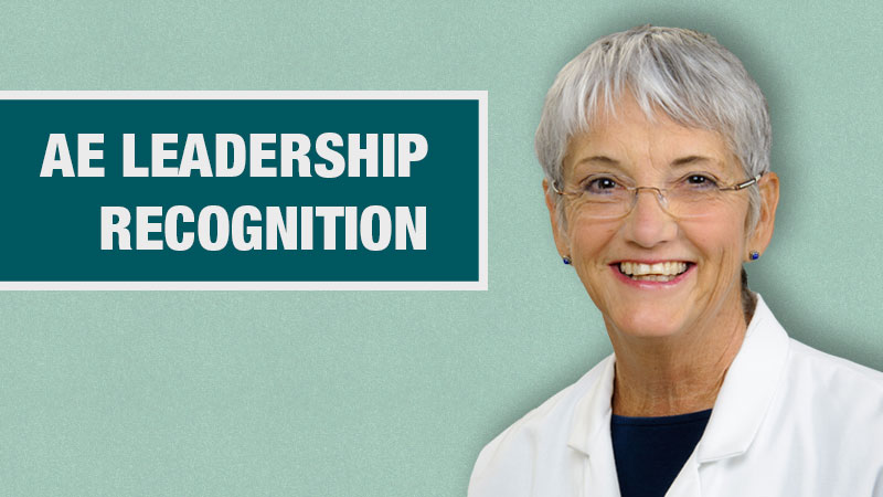 Graphic with a light teal background showing a person in a white lab coat beside a dark teal box containing the text ‘AE Leadership Recogition.’