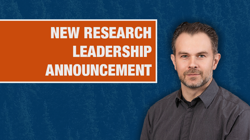 Graphic with a blue textured background showing a person in a grey dress shirt beside an orange box containing the text ‘New Research Leadership Announcement.’