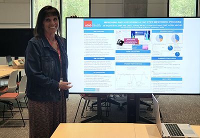 Dr. Jill Bryant Bova stands next to her poster, looking at the camera smiling.