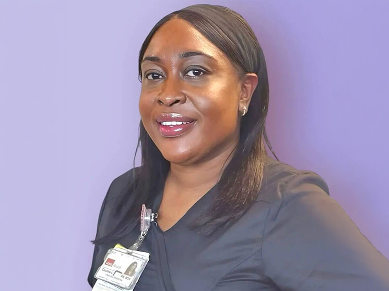DAISY Award recipient, Claudine Witter, smiles in front of a purple backdrop.