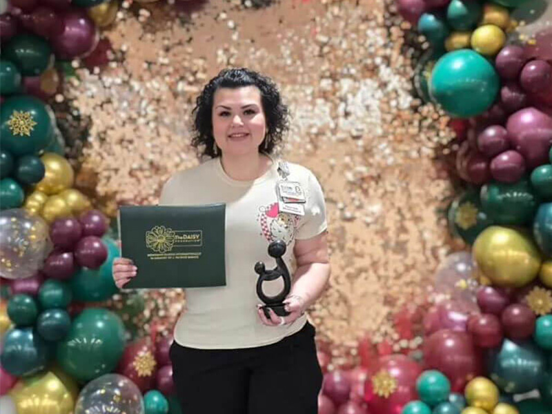 DAISY Nurse Leader Award recipient, Evelyn Mendez, smiles holding her certificate and award.