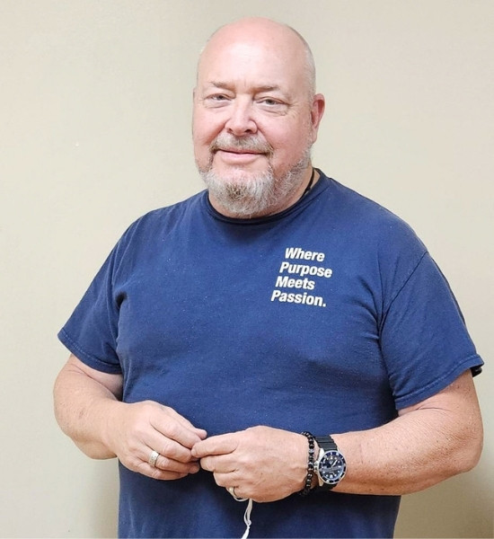 Dunne Dittman, Patient Care Technician, smiling in a shirt that reads, "Where Purpose Meets Passion."
