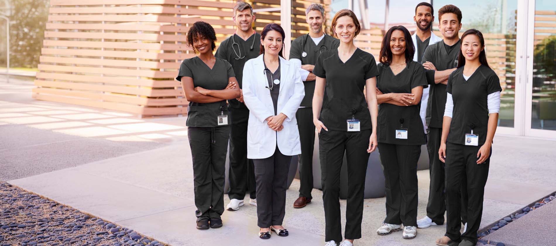 Group of smiling male and female doctors and nurses standing outside