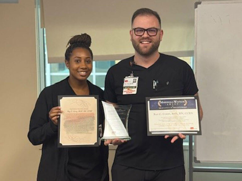 2025 Marshall-Watson Award recipient, Ray Corry, smiles holding his award and certificate next to his preceptee holding his nomination letter.