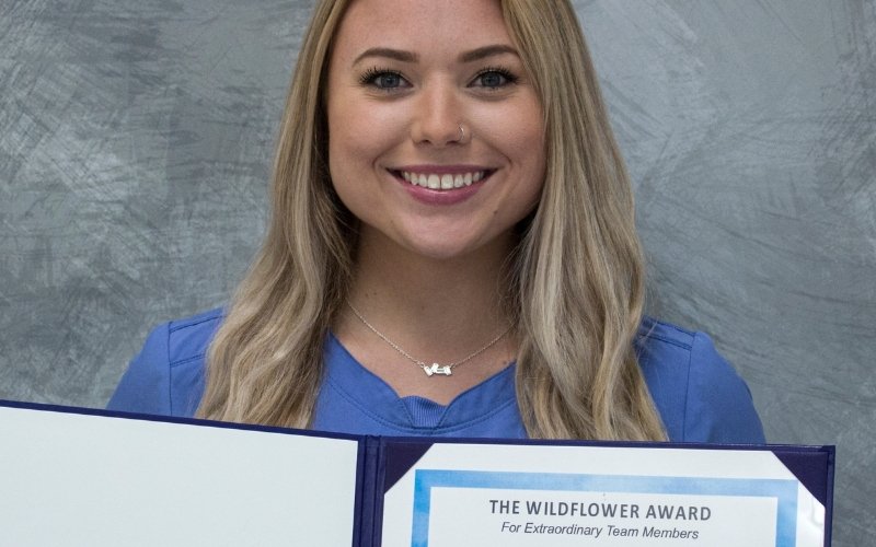A Wildflower Award Recipient smiles and poses with her certificate. 