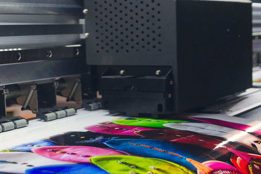 A large format printer is producing a colorful high resolution banner used for UTMB design and printing projects.