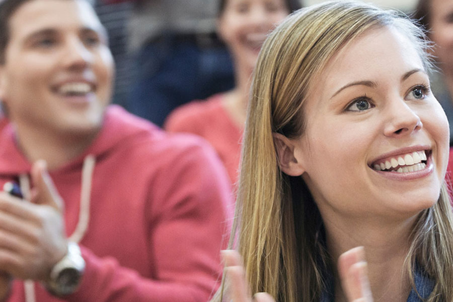 Smiling woman clapping in a cheering crowd at a public event