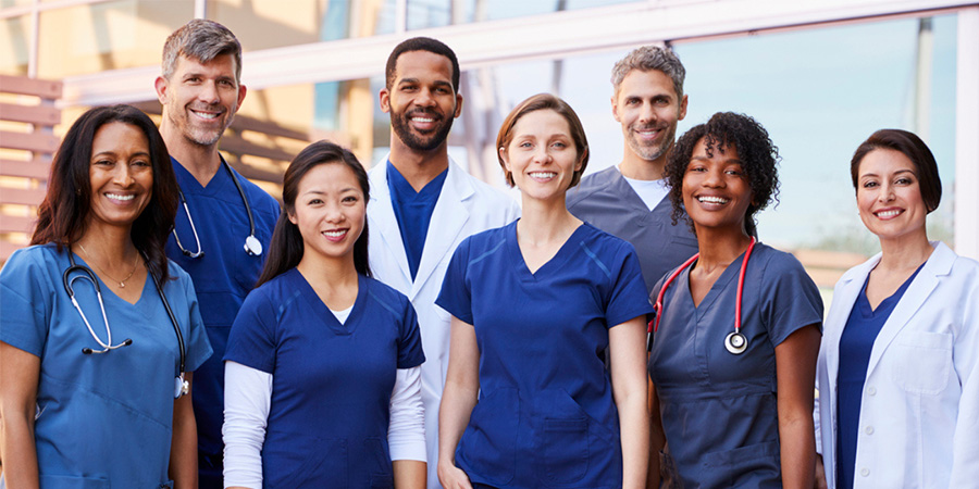 A group of diverse medical workers in scrubs and labcoats.