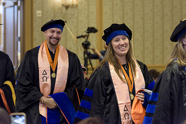 Two graduates in caps and gowns smiling