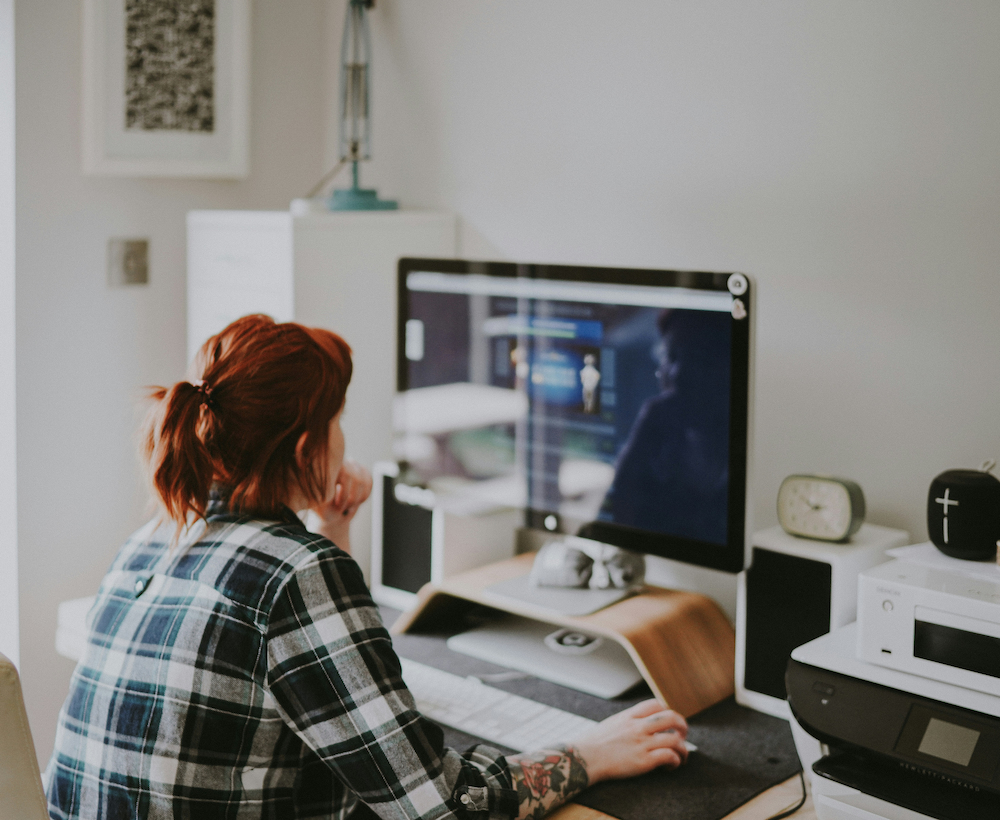A working professional looking at a computer monitor in a home office
