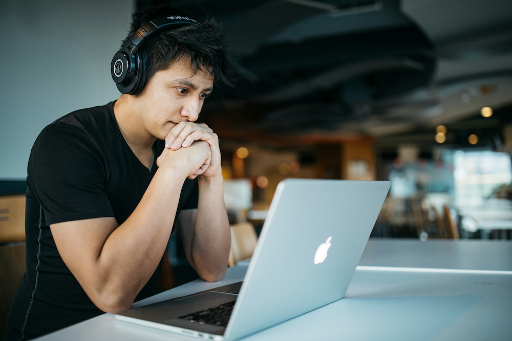 A man with headphones looking at a screen