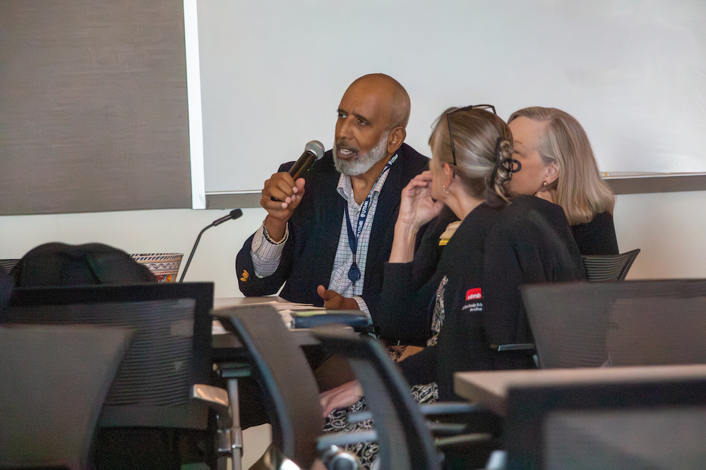 Charles Mouton remarks Dr. Mouton speaks into a handheld microphone in front of the presentation screen during the session.
