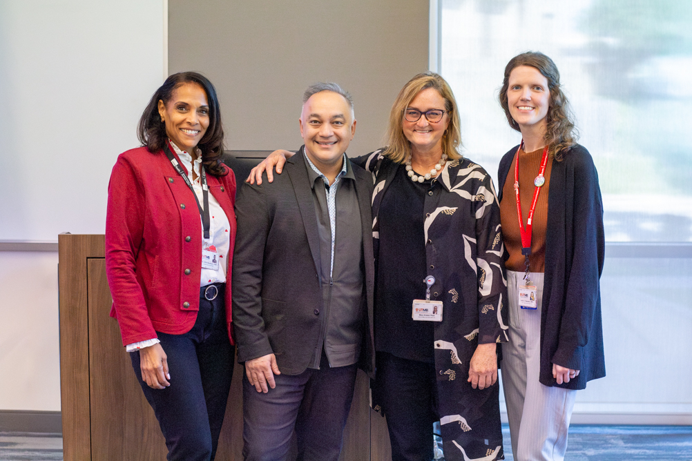 Four attendees pose together for a photo at a public health symposium.