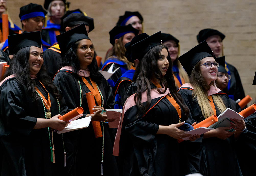 A candid shot of a group of UTMB students standing at commencement in May 2025
