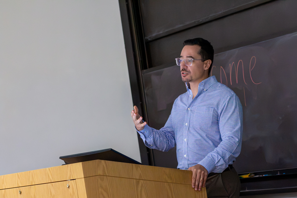 Dr. Alberto Aparicio gestures while delivering a seminar from a classroom lectern.