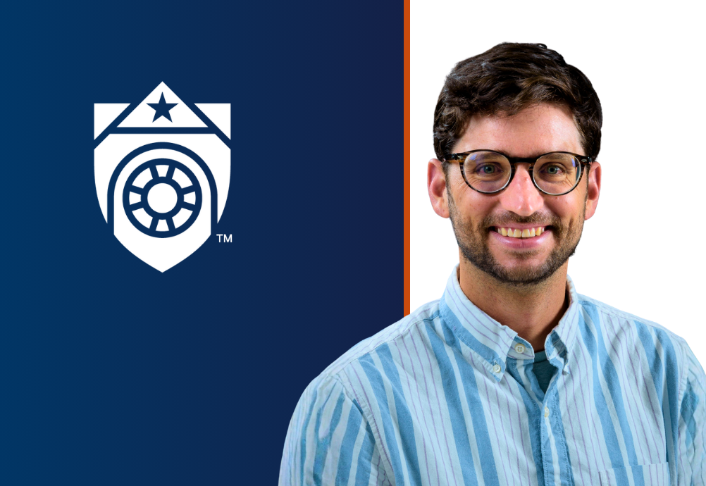 Brian Downer, wearing a light blue striped shirt, beside the white UTMB shield on a navy panel, with an orange vertical line dividing the navy and white background.