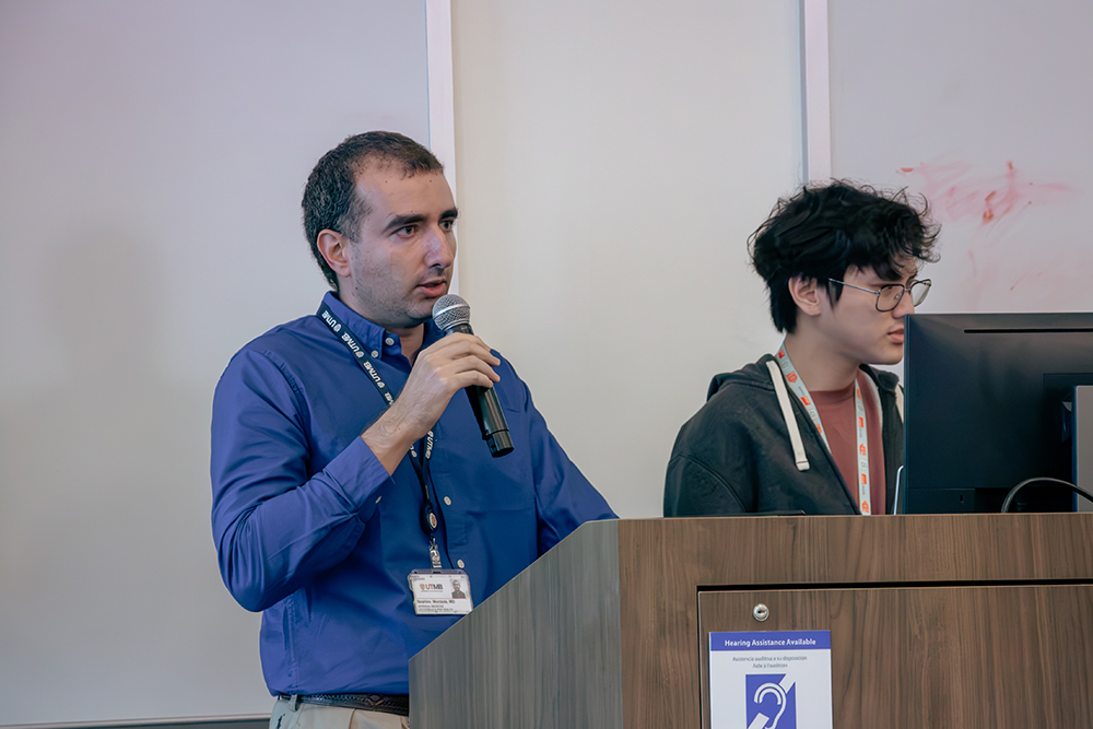 IMG_3038 Ibrahim Mortada presents his team's analysis of antiviral drugs and Alzheimer's risk while a teammate runs the slides.