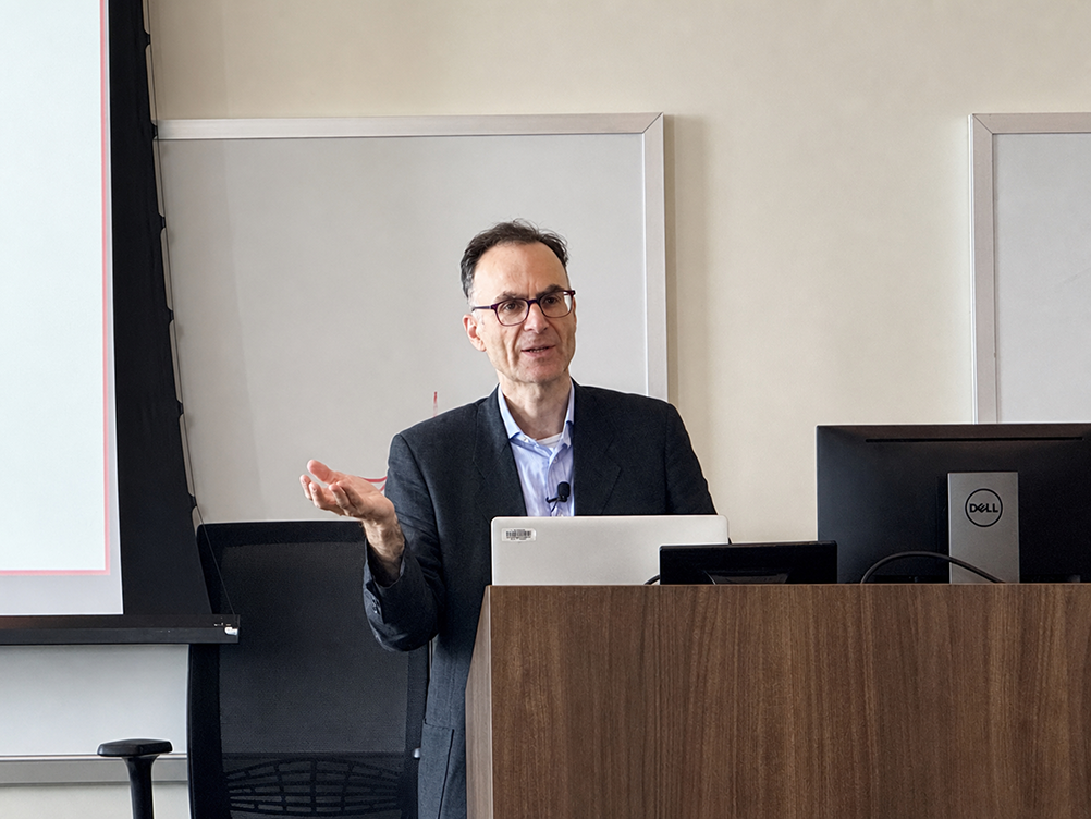 Seena Fazel gestures while presenting from a lectern during his seminar on suicide and self-harm risk in correctional settings.