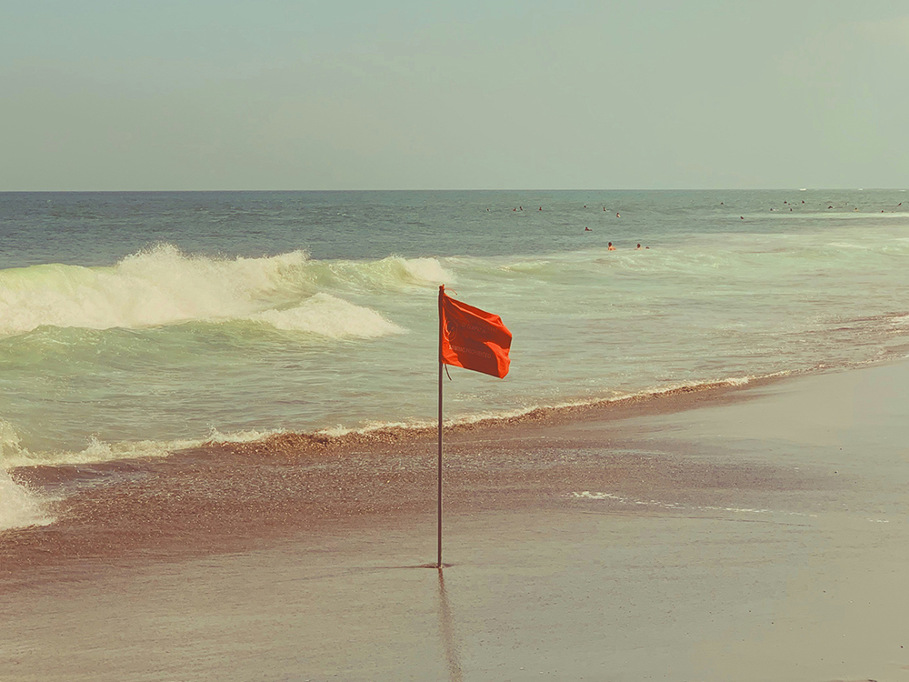 A red flag stuck in the sand at the beach