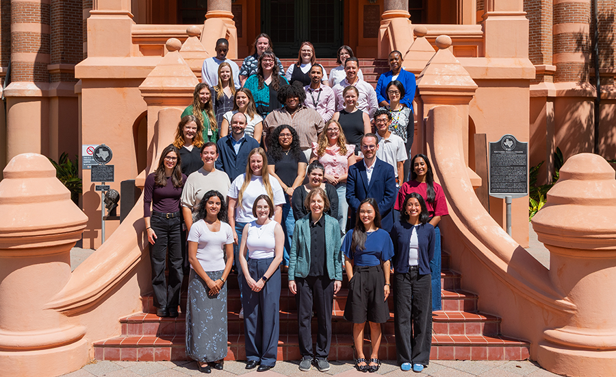 A large group poses together on the steps of a UTMB building.
