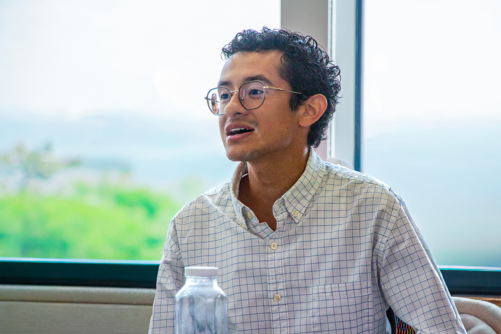A student speaks during a discussion in a sunlit room.
