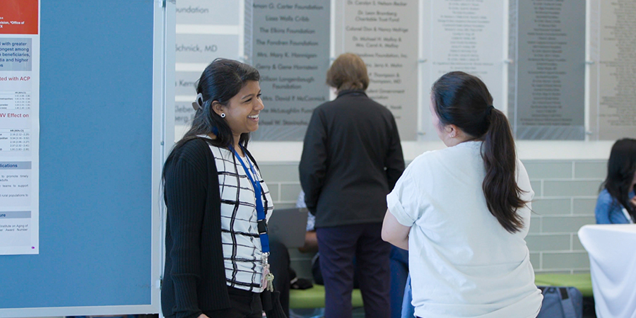 Two researchers discuss a scientific poster during a UTMB research event.