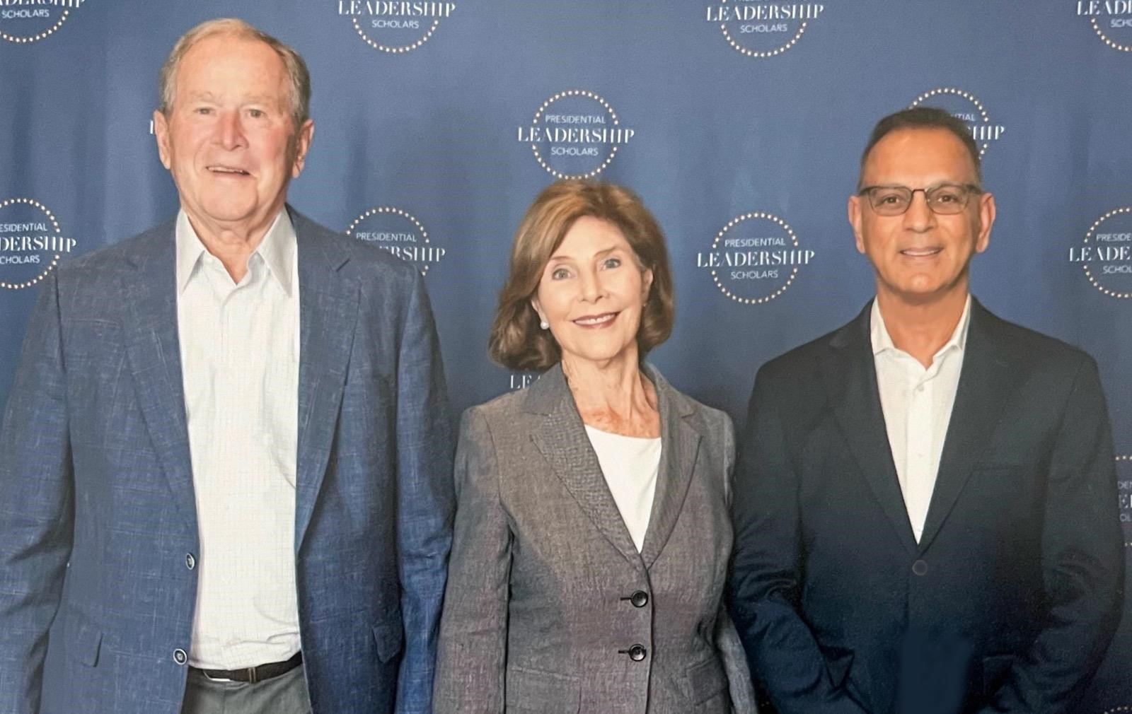 Dr. Suresh Bhavnani standing with President George W. Bush and Laura Bush in front of a Presidential Leadership Scholars backdrop.