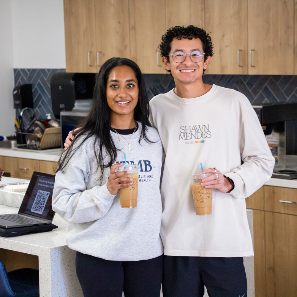 Two students sitting at a counter with drinks, working together during a Writing Accountability Group session
