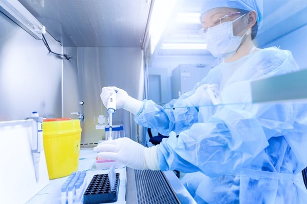 lab personnel distributing samples in vials in a safety cabinet