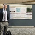 Dr. Abraar Karan posing in front of poster