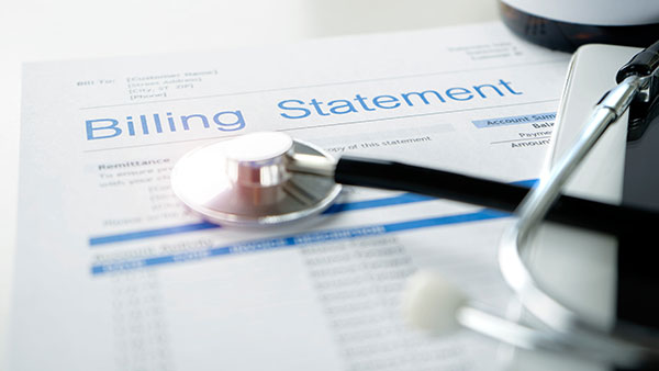 The corner of a billing statement with a stethoscope resting on top of it