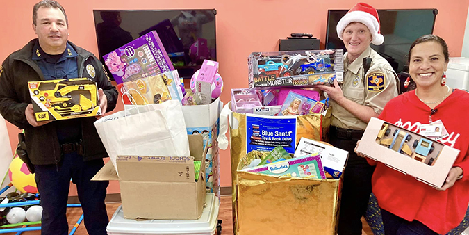 Members of the UTMB Police Department and a colleague show off donations collected for the 2024 Blue Santa drive.