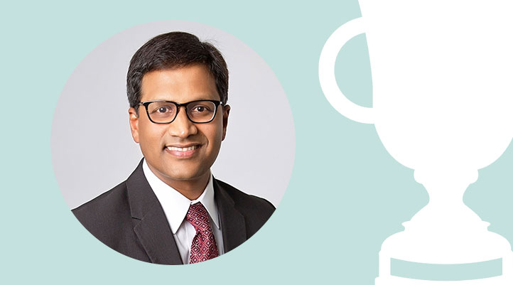 Headshot of Dr. Alok Makam on a light teal background with a white trophy graphic