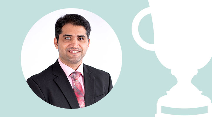 Headshot of Dr. Irfan Masood on a light teal background next to a white trophy graphic