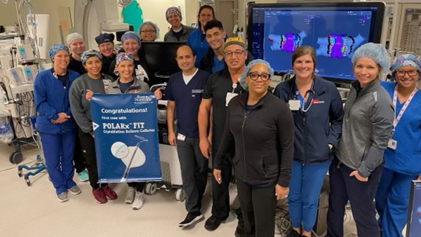 A group of medical professionals stands together around a sign commemorating the first POLARx procedure.
