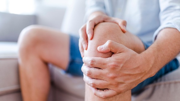 A close up photo of a person's hands clutching their knee as they sit