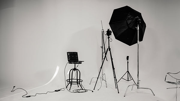 Photo shoot equipment including a stool, camera, and umbrella in a white room