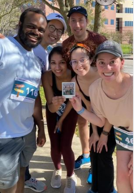 The running program has helped to build community while promoting health and fitness. Students huddle together smiling at the camera.