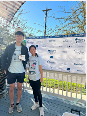 Runners celebrated their achievements at a community finisher festival. Two runners stand in front of a banner listing sponsor names.