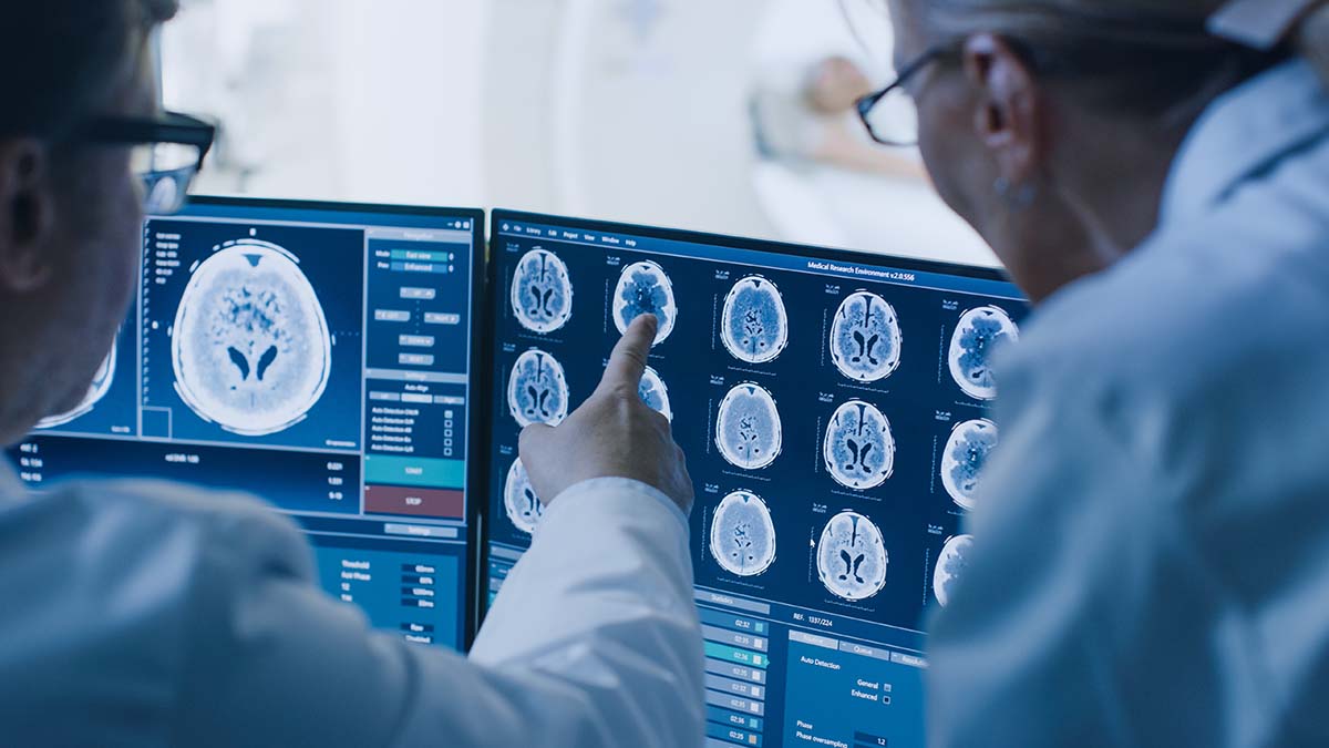 Two medical professionals look at brain scans on a computer