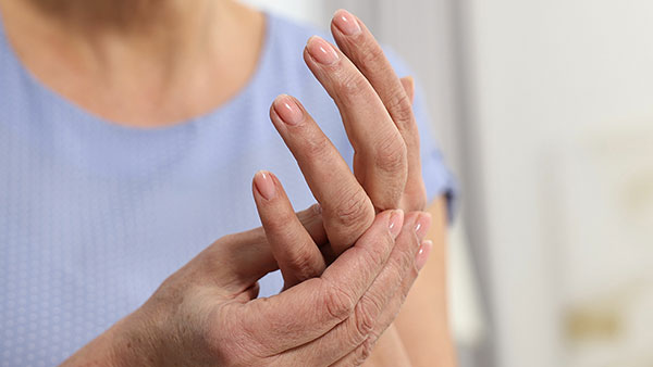 A woman touches the joints in her hand as if in pain