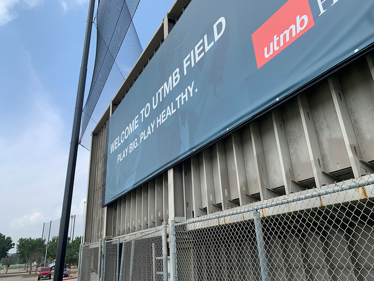 A sign on the outside of a baseball field that says "Welcome to UTMB Field."