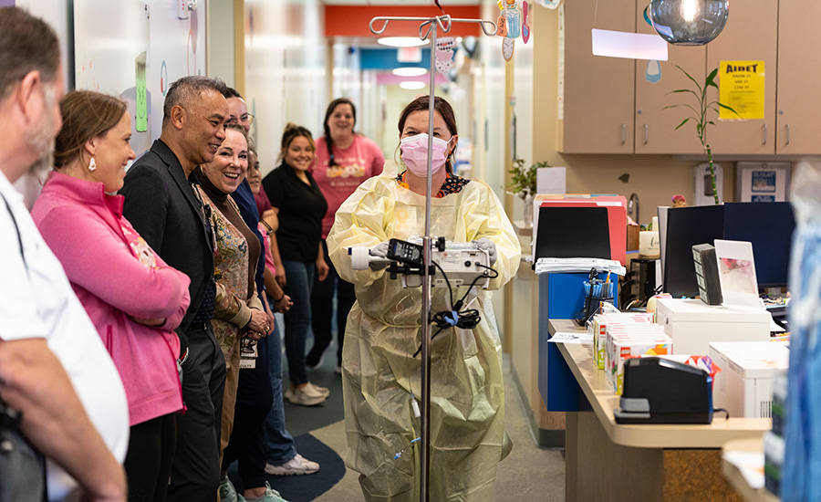 Julie Hanson, UTMB Health nurse, prepares for Jose's gene therapy treatment Julie Hanson, walking down a clinic hall with the gene therapy medication cheered on by employees and family